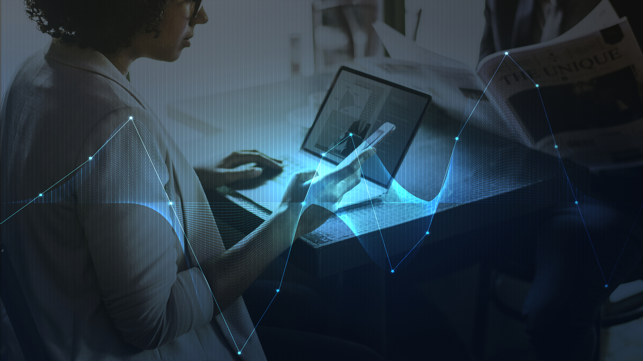 grafika Kobieta korzystająca z laptopa i smartfona w środowisku biurowym, z nałożoną wizualizacją danych i wykresami – symbol rozwoju fintechu i cyfrowej gospodarki w Polsce